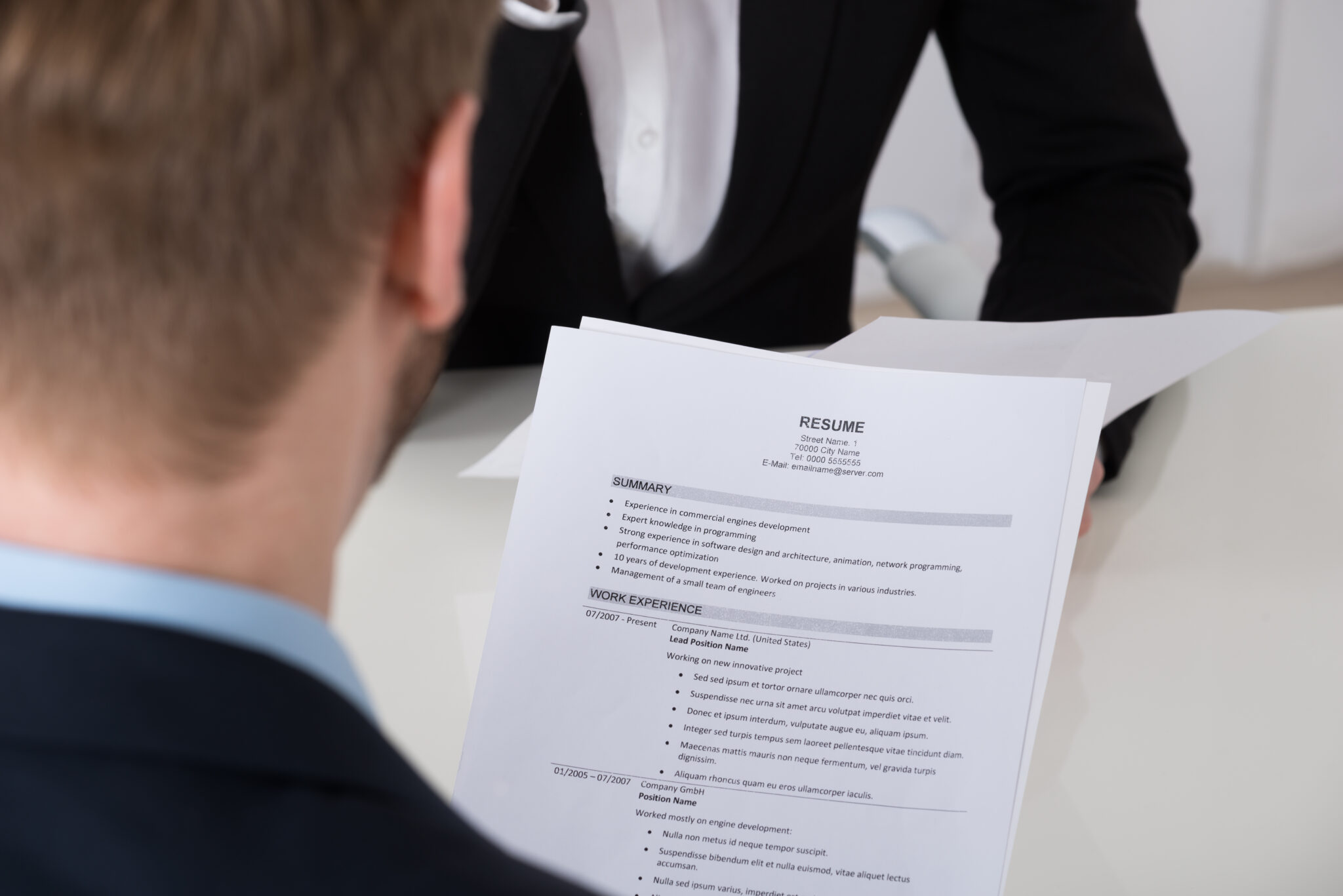 Close-up Of Businessman Analyzing Resume At Desk In Office
